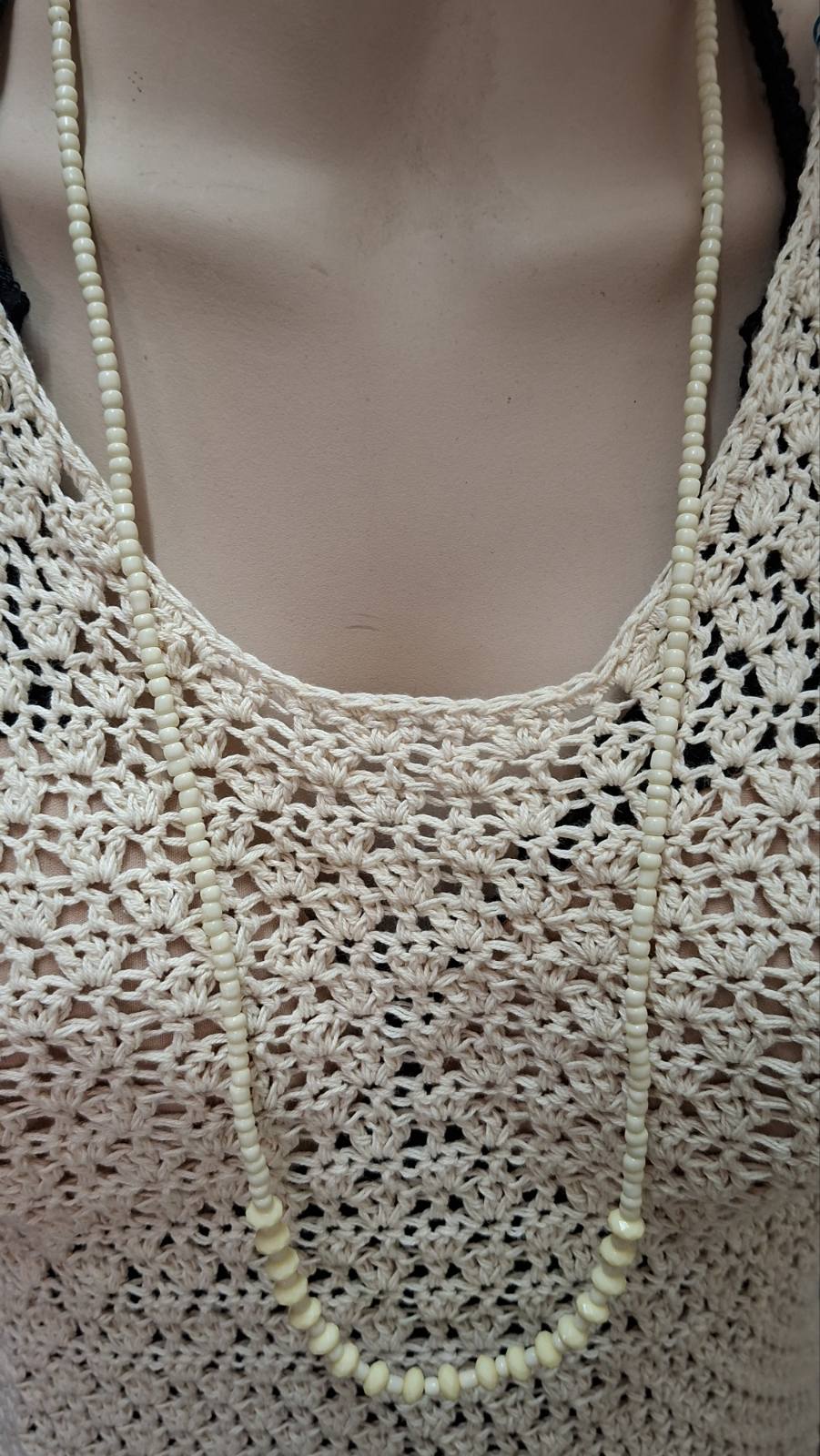 Ivory beaded long necklace worn on mannequin with crochet top