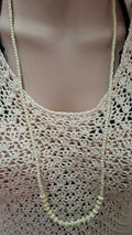 Ivory beaded long necklace worn on mannequin with crochet top