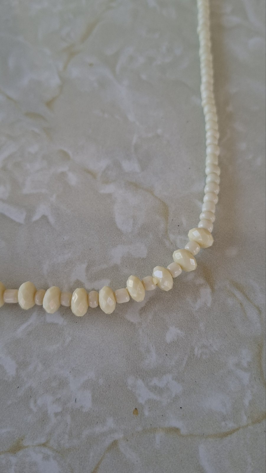 Close-up of ivory faceted rondelle focal beads on white background