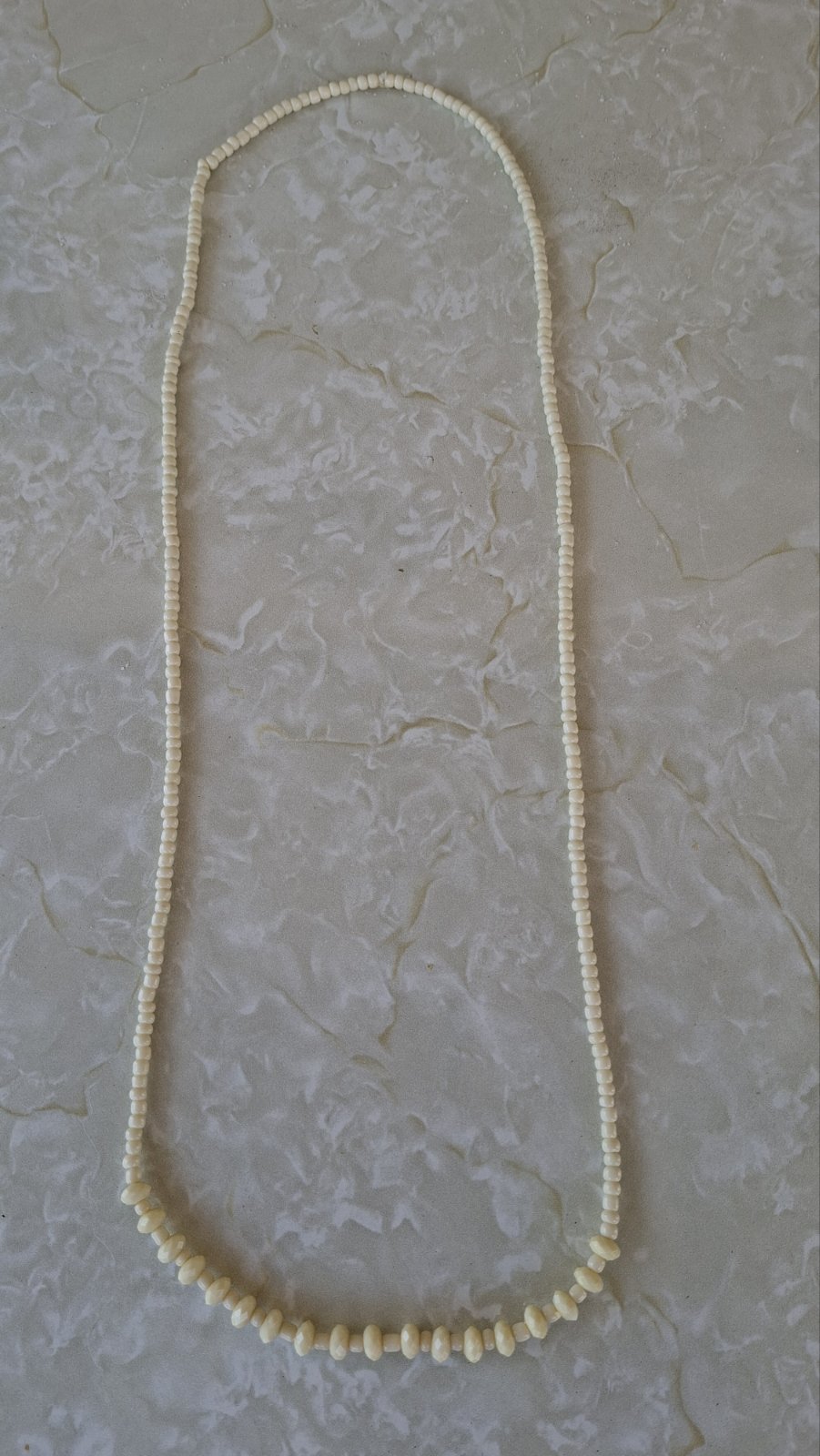Full length ivory beaded necklace laid flat on white background