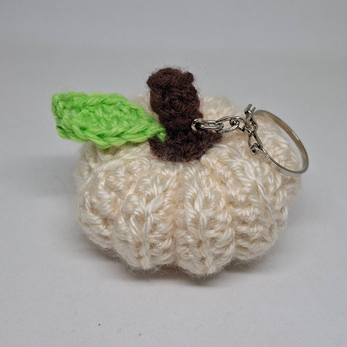 Cream crochet pumpkin keyring with green leaf and brown stalk