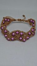 Macramé pearl bracelet in mauve laid flat on white background
