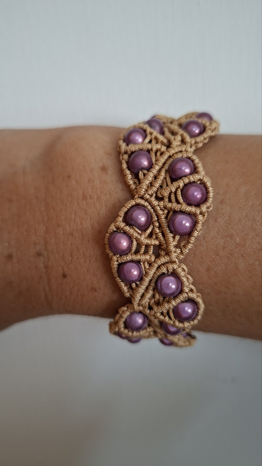 Macramé pearl bracelet in mauve worn on wrist