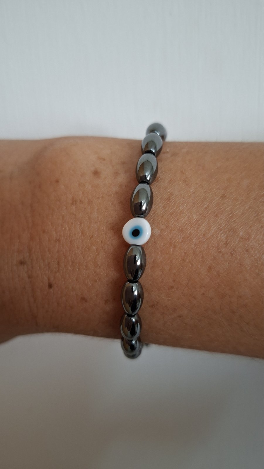 Hematite evil eye bracelet worn on a wrist