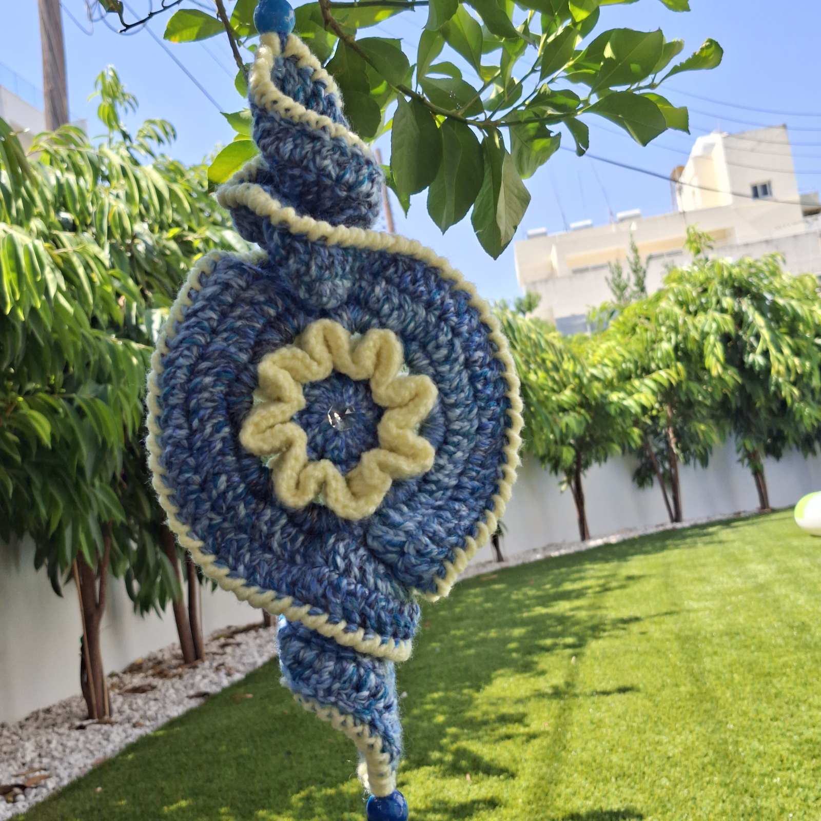Close-up of handmade crochet evil eye spiral garden hanging outdoors – Georgia Create Cyprus