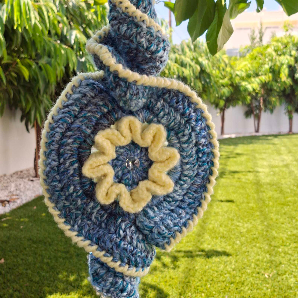 Frond view of handmade crochet evil eye spiral decoration hanging outdoors – Georgia Create Cyprus