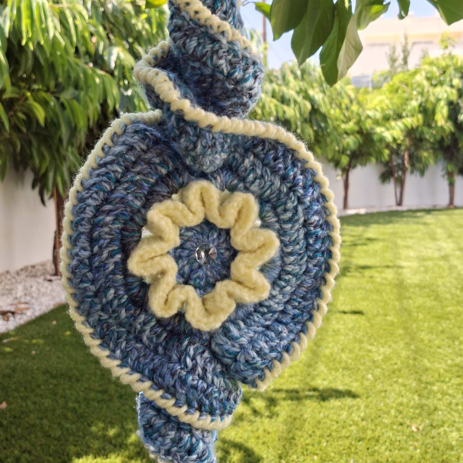 Frond view of handmade crochet evil eye spiral decoration hanging outdoors – Georgia Create Cyprus