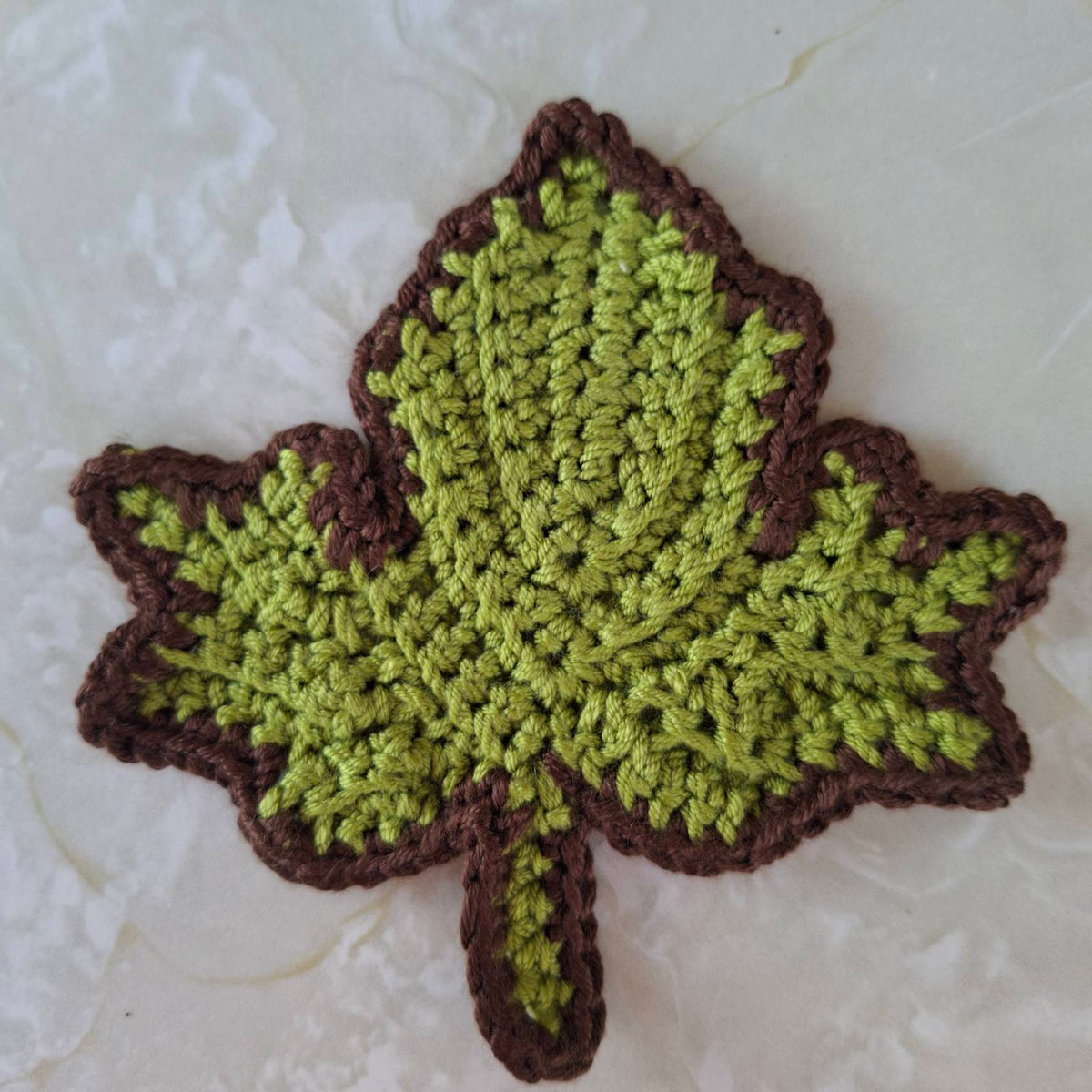 Green crochet leaf coaster with brown edging
