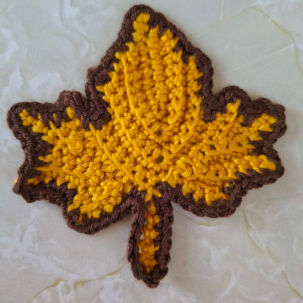 Mustard yellow crochet leaf coaster with brown edging