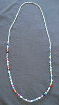 Multicolour beaded necklace laid flat on a dark background