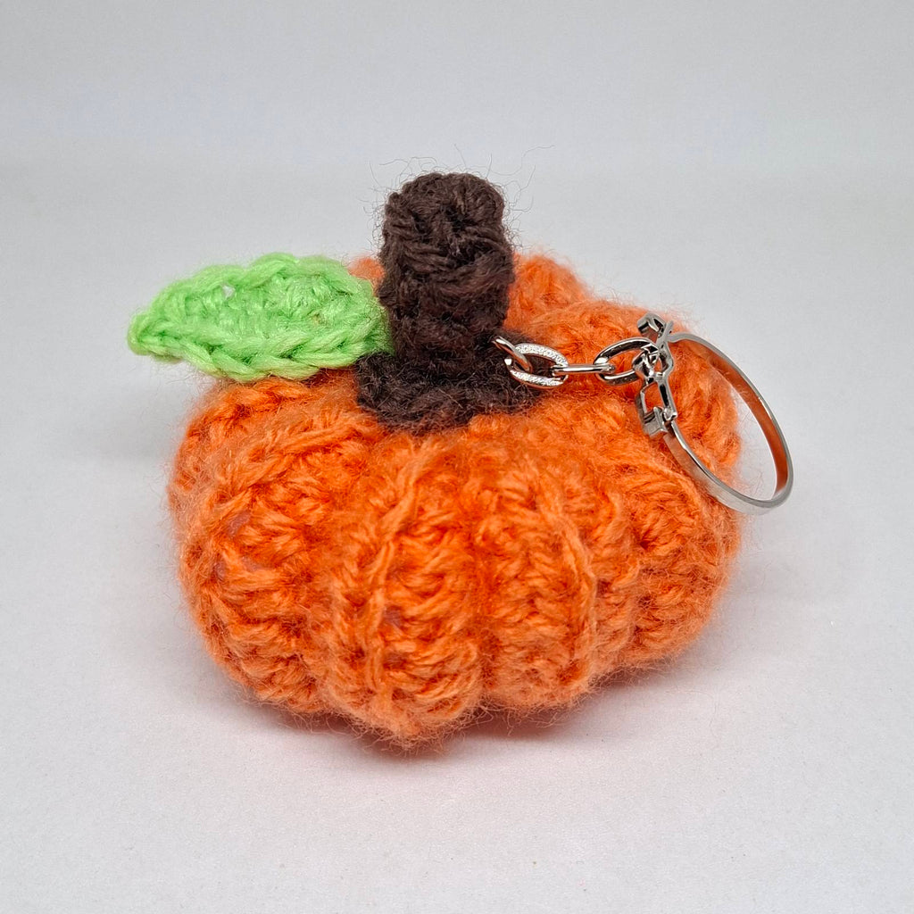 Orange crochet pumpkin keyring with green leaf and brown stalk