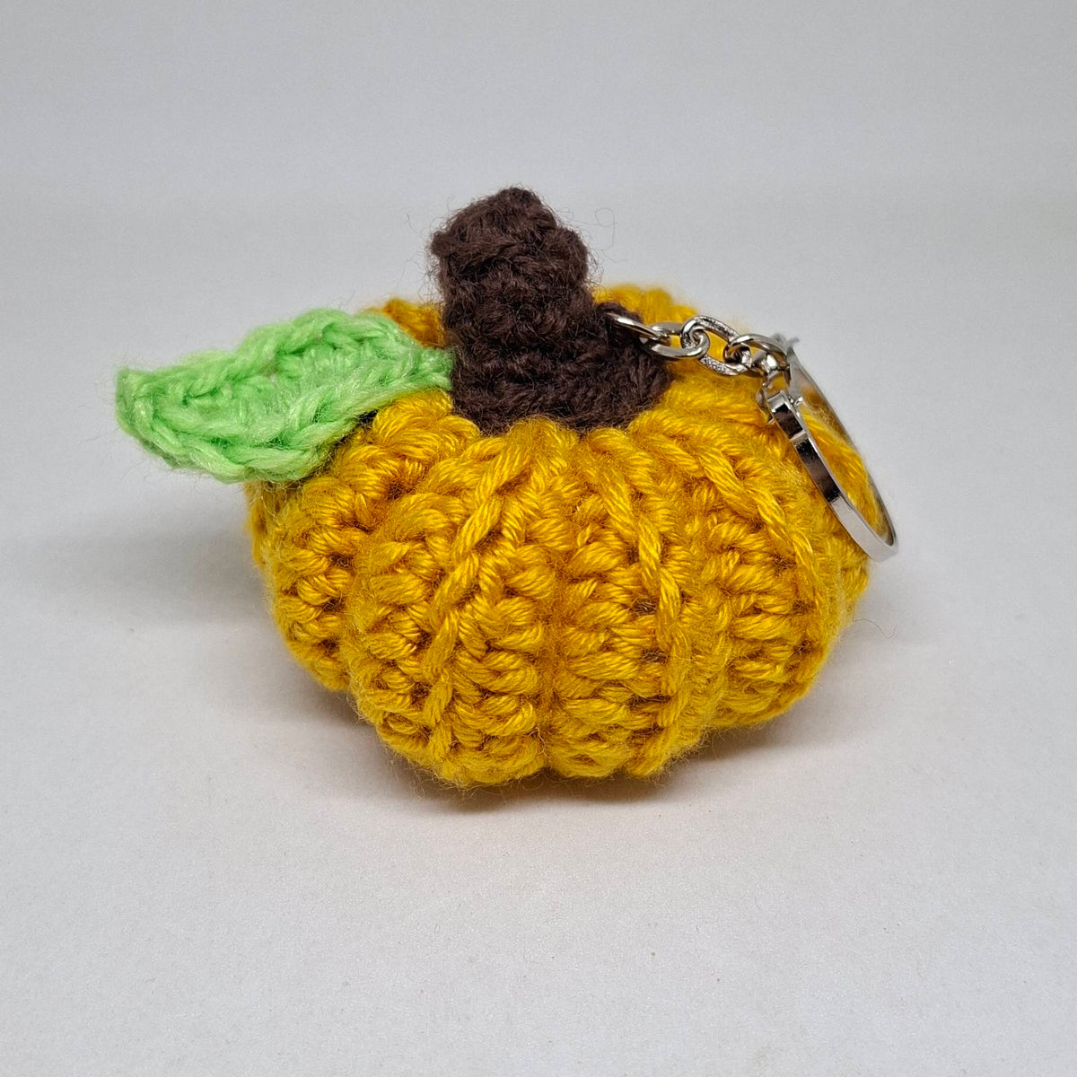 Yellow crochet pumpkin keyring with green leaf and brown stalk